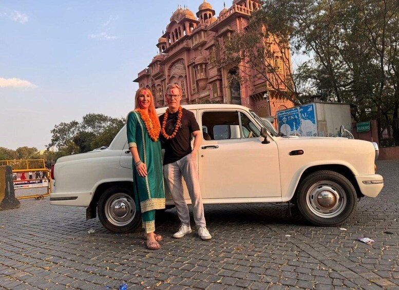 A vintage white car parked in front of a historic building with intricate architecture. 3