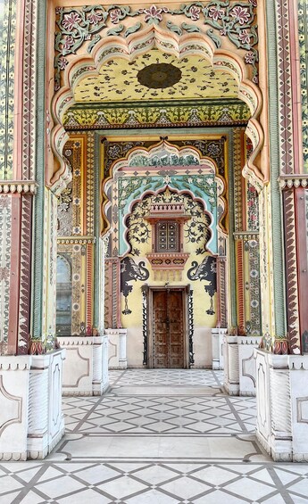 An ornate entrance with intricate floral and geometric patterns, a tiled floor, and a central doorway framed by decorative columns. 1