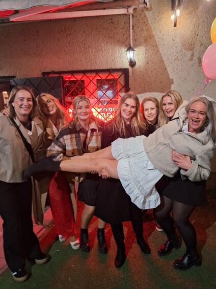 A group of people holding hands in a line, with a neon sign in the background. 3
