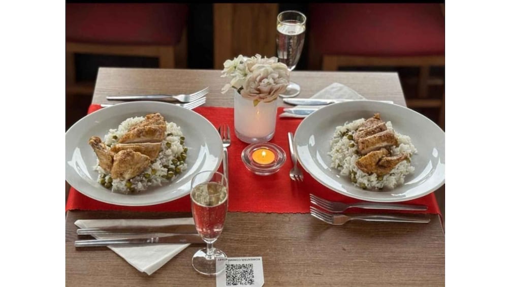 Two plates of rice and chicken, a candle, and a QR code on a table. 1