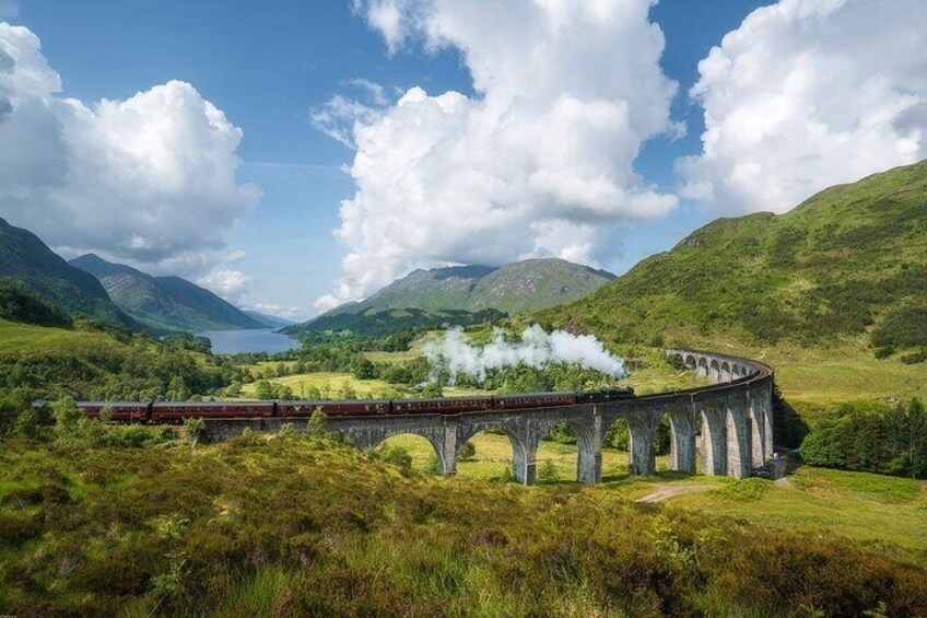 A train on a bridge over a valley with mountains in the background. 1