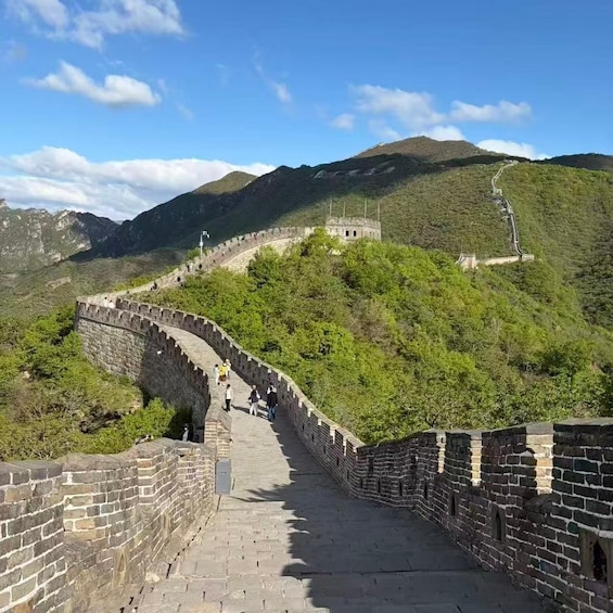 The Great Wall of China winding through a mountainous landscape with visitors walking along the path. 2