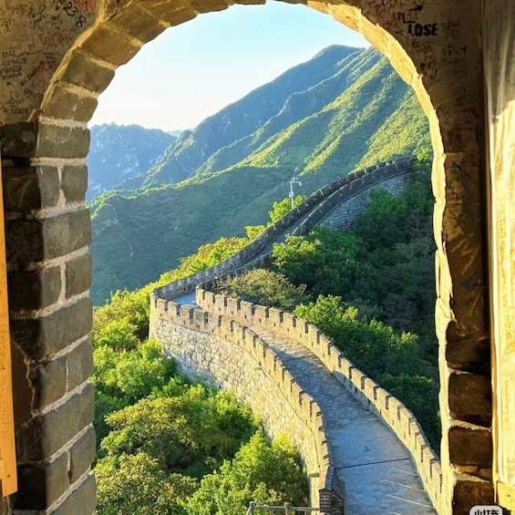 A section of the Great Wall of China with a stone walkway, surrounded by lush green mountains. 5