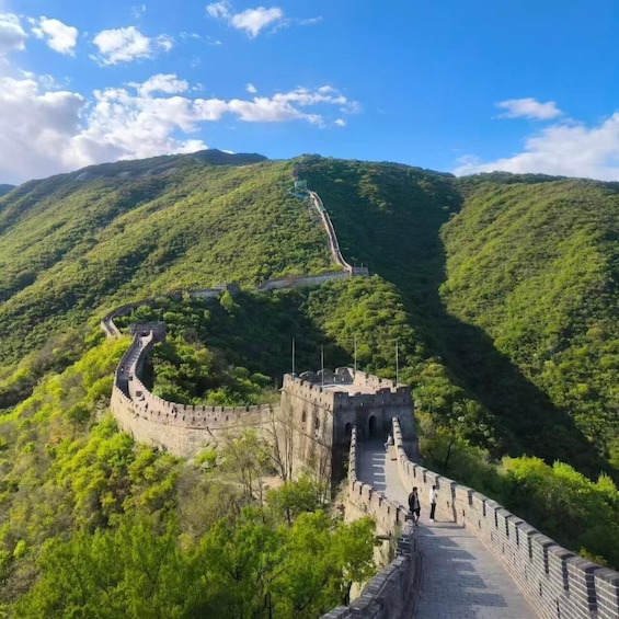 The Great Wall of China winding through lush green hills under a clear sky. 4