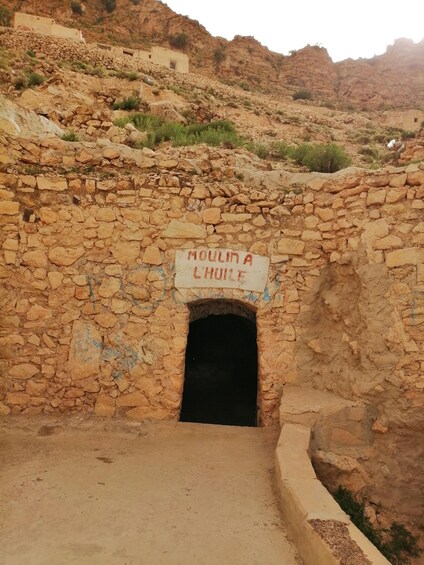 A stone structure with a sign reading "Moumina L'Chouil". 5