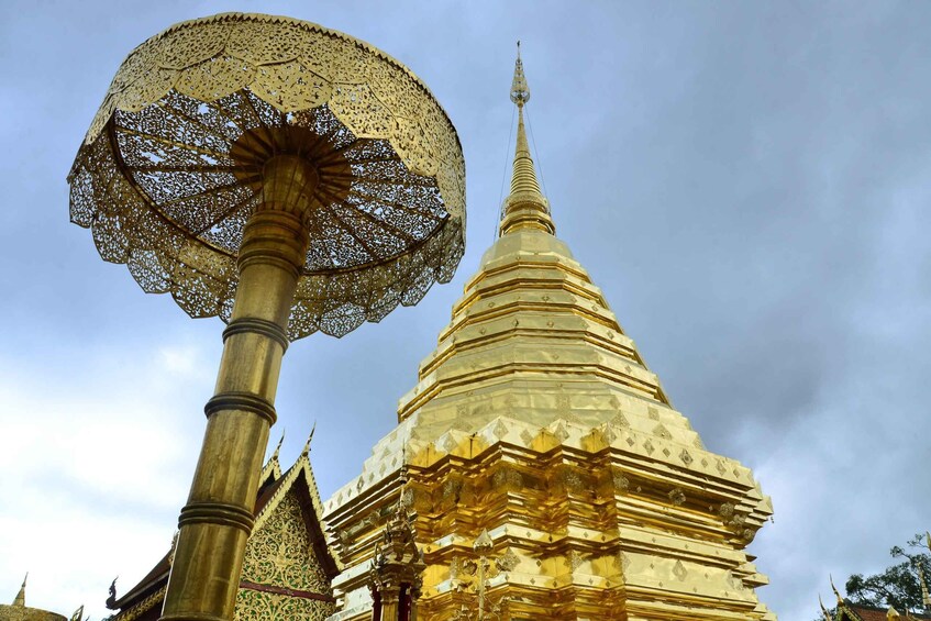 A golden stupa with intricate patterns and a large umbrella-like structure in front. 4