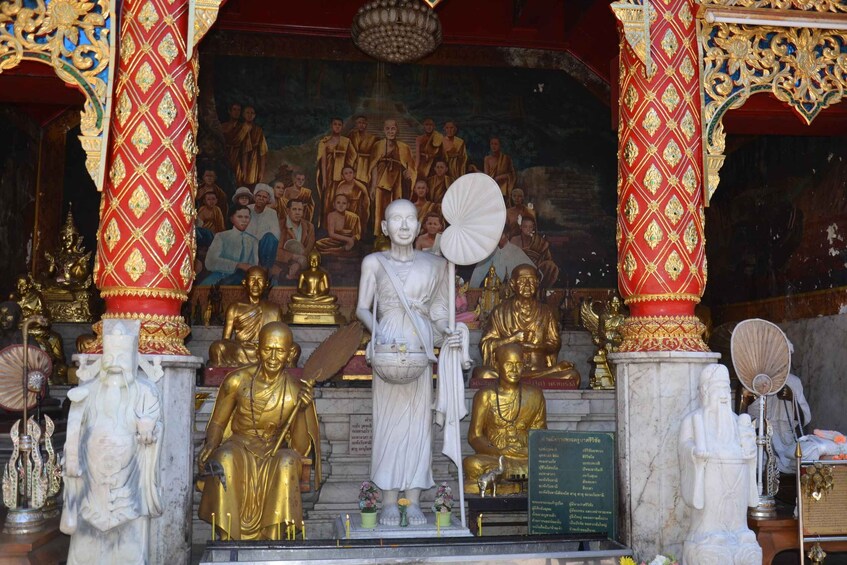 A temple interior with golden statues, intricate carvings, and a central white statue. 3