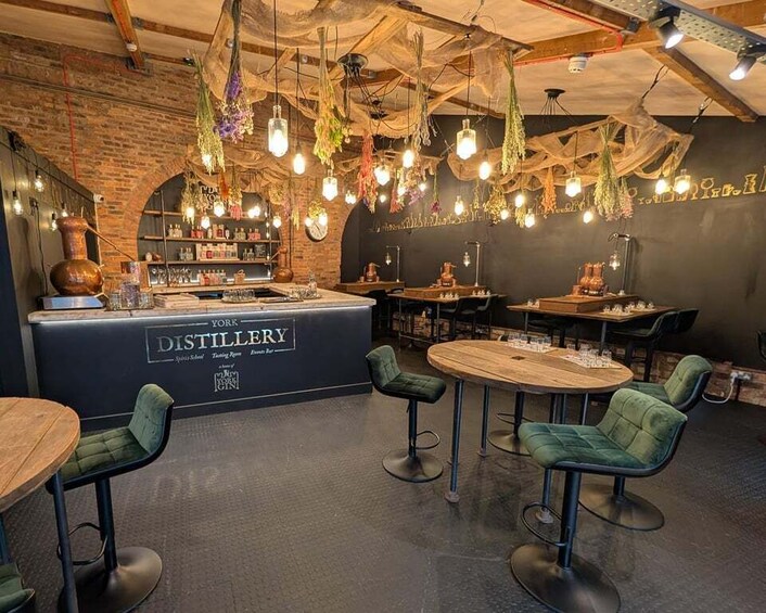 A cozy bar with green upholstered chairs, a wooden bar counter, and hanging light fixtures. 4