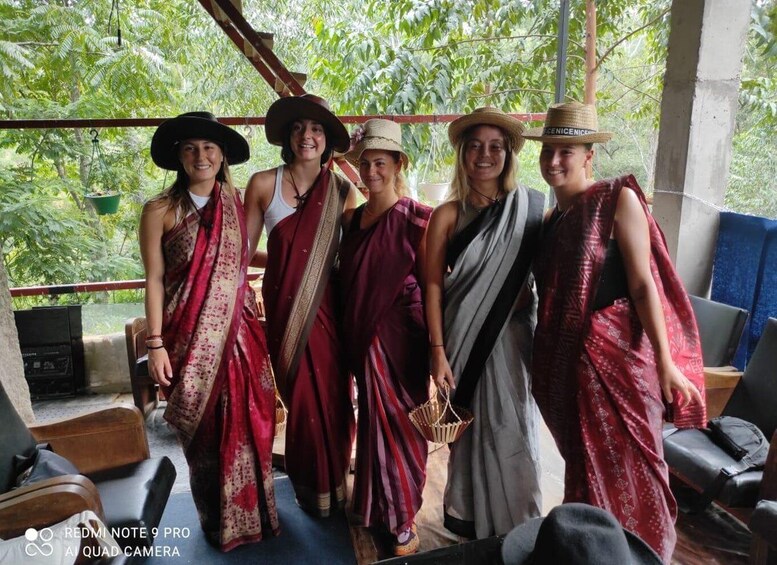 A group of people in traditional attire standing on a balcony with a view of lush greenery. 5