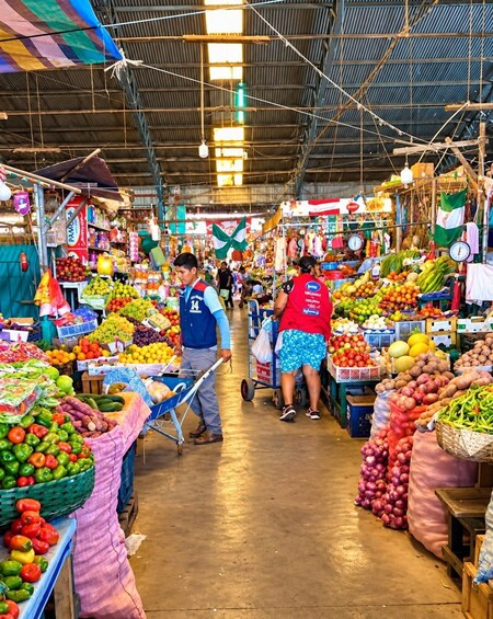 An indoor market with various stalls selling fruits, vegetables, and other goods. 3