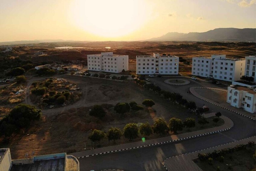 A residential area with apartment buildings, a winding road, and a sunset in the background. 4