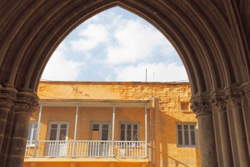 A building with a balcony under a stone archway. 5