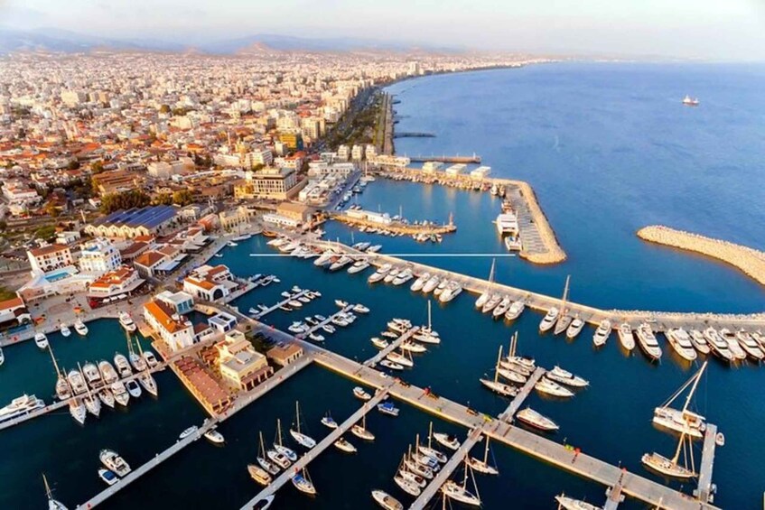 An aerial view of a coastal city with a marina filled with boats, a long pier, and a densely built urban area. 3