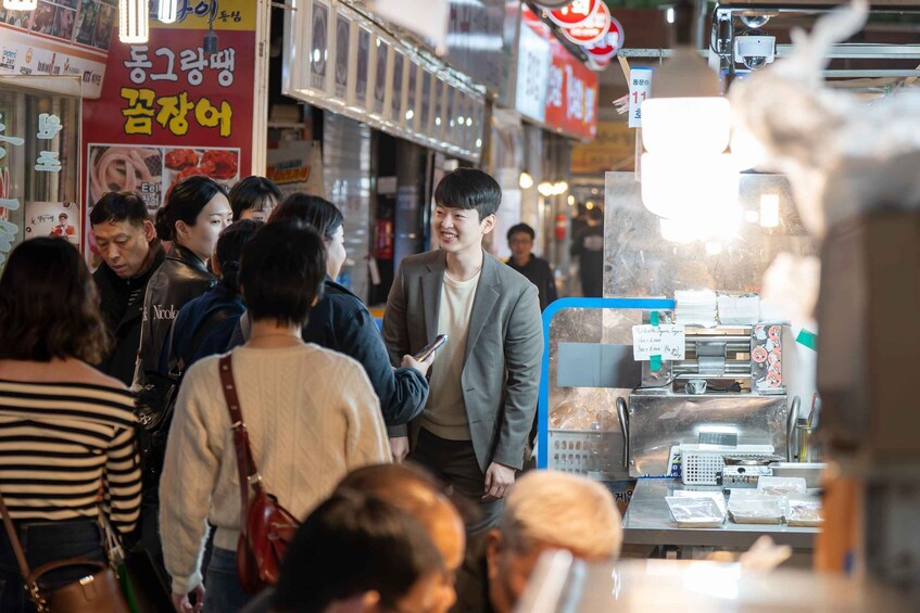 A busy street market with people shopping and a food stall in the foreground. 4