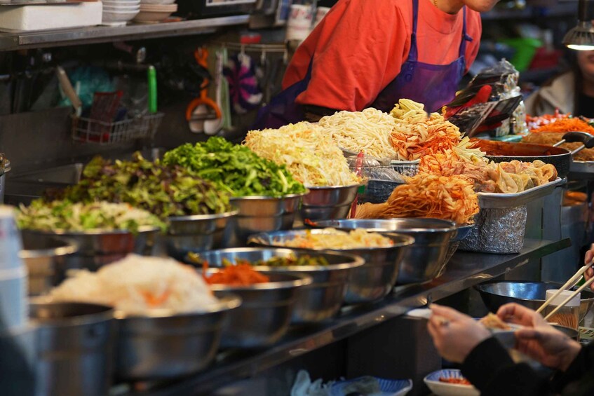 A food stall with various dishes, including noodles and vegetables. 1