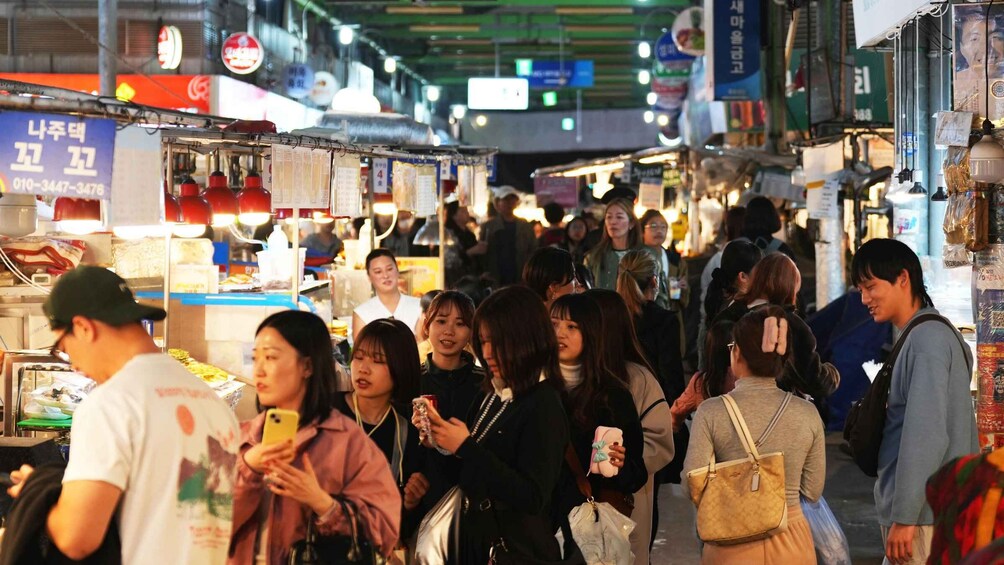 A crowded market with people shopping and vendors selling goods. 2