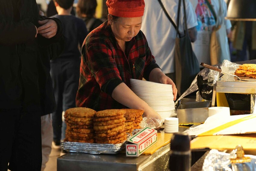 A person preparing food at a street food stall. 5