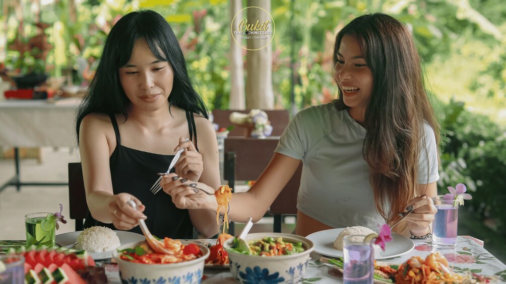 Two people dining outdoors with a variety of dishes and drinks on the table. 5