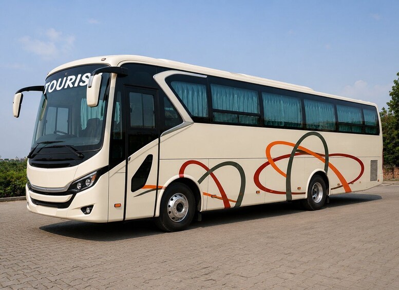 A white tour bus with 'TOURIS' on the front windshield, parked on a paved surface. 3