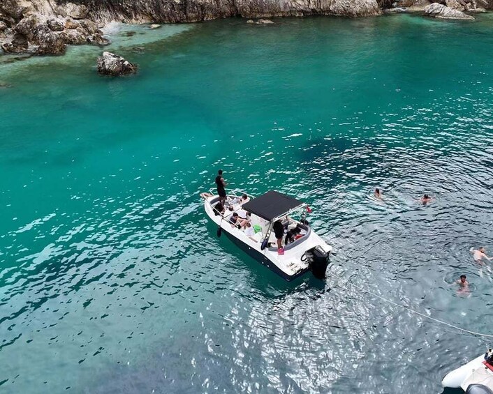 A boat with people on a turquoise body of water surrounded by rocky terrain. 1