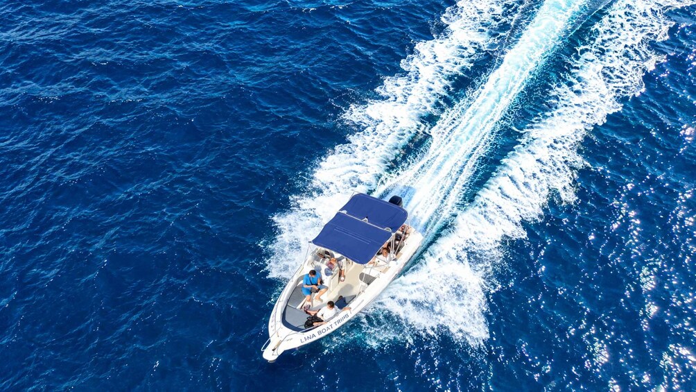 A boat with a blue canopy sailing on a deep blue sea. 2