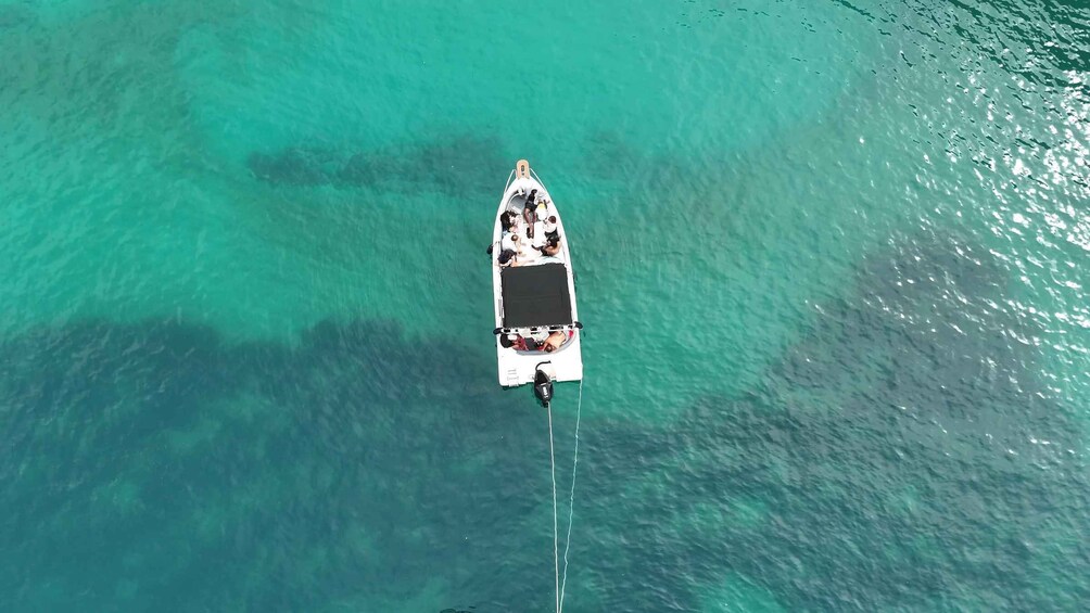 An aerial view of a small boat on clear turquoise water. 4