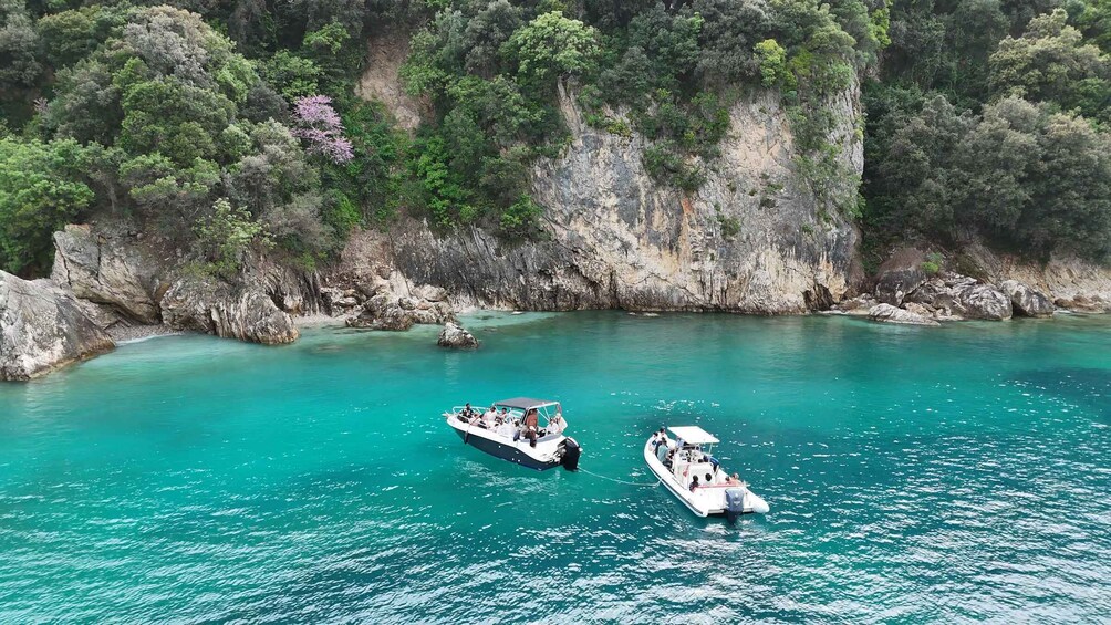Two boats on turquoise waters surrounded by rocky cliffs and dense greenery. 5