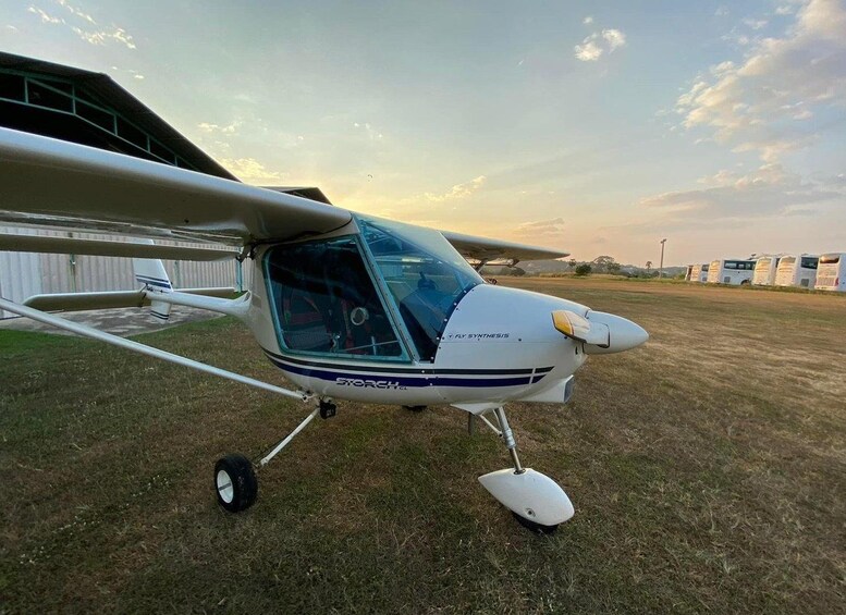 Una aeronave pequeña estacionada sobre césped, con un hangar al fondo. 2