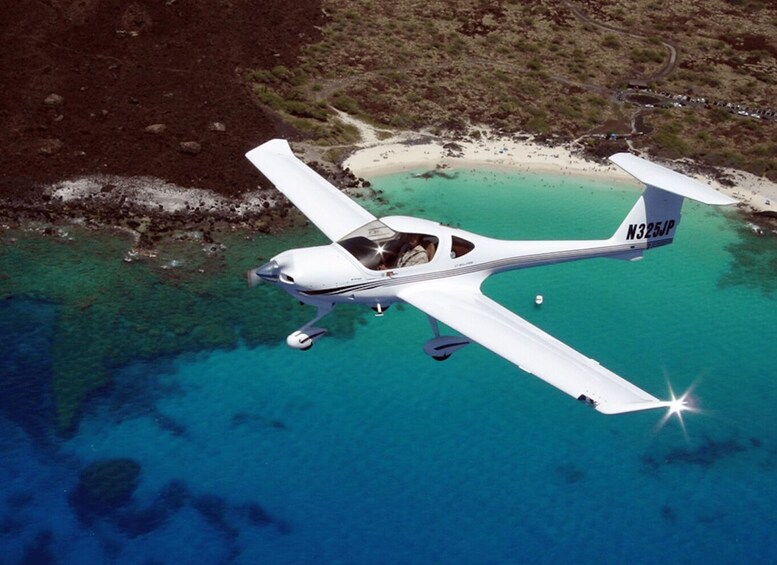 A small aircraft flying over a coastal area with clear blue waters and a sandy beach. 2
