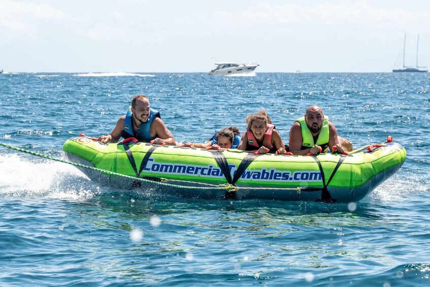 A green inflatable boat with four people wearing life jackets on the water. 3