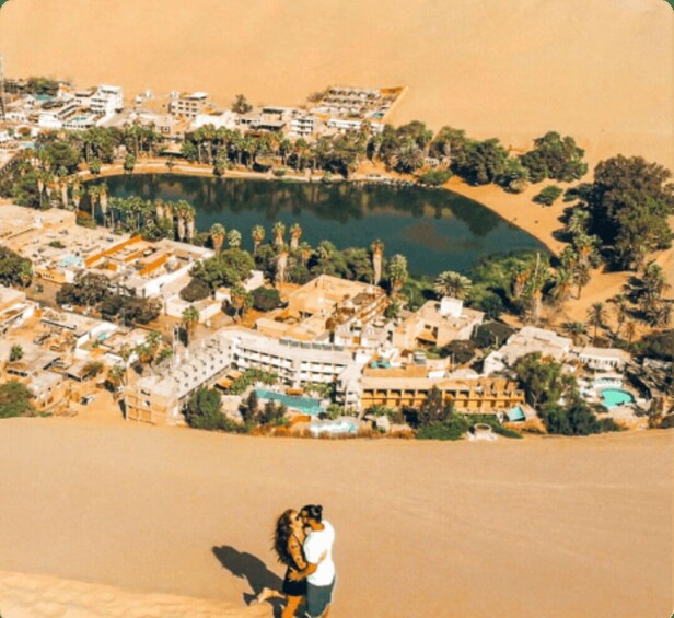 A desert landscape with a large body of water, palm trees, and buildings. 2