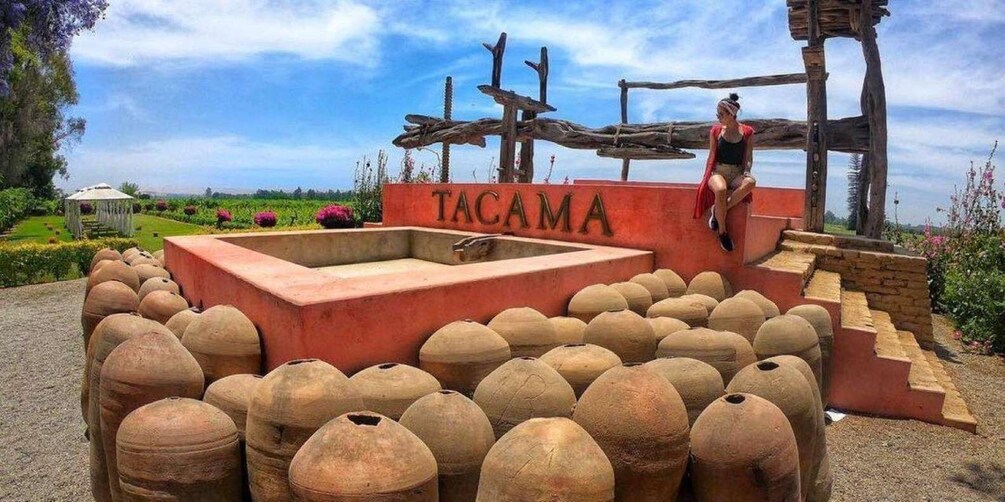 A historical site with a sign reading "TACAMA" surrounded by large clay pots. 4