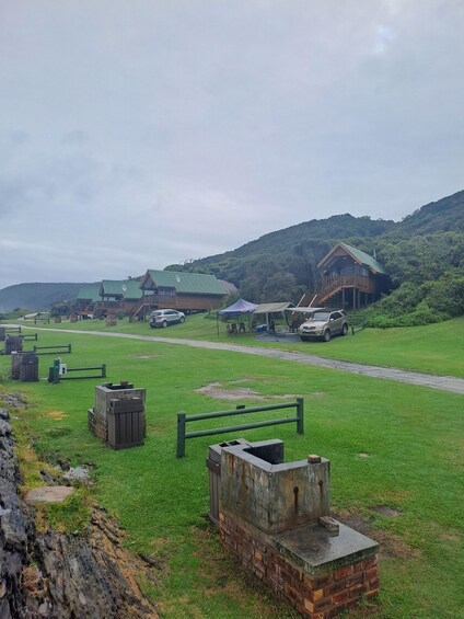 A grassy area with wooden structures and a hill in the background. 2