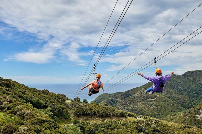 Two people zip-lining over a mountainous landscape. 5