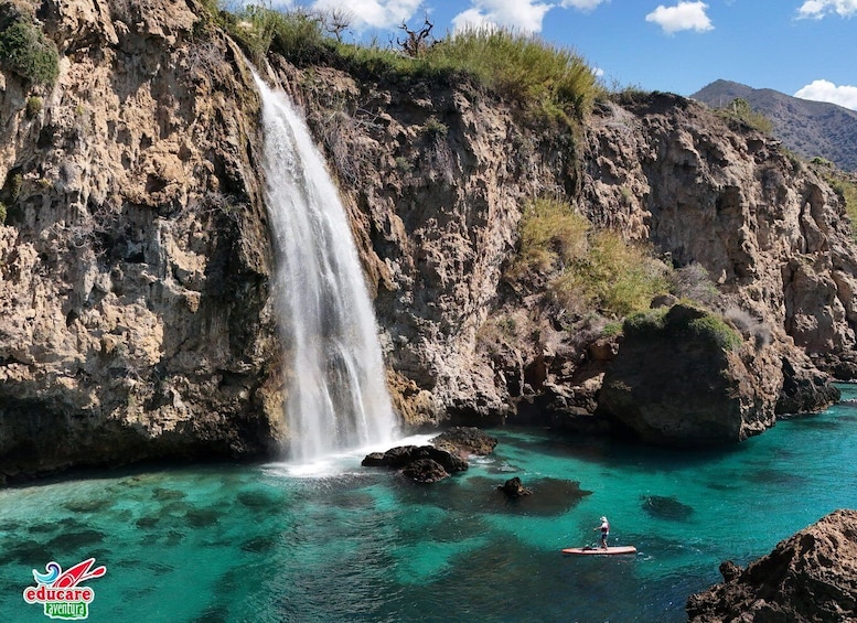 A waterfall cascading into turquoise waters surrounded by rocky cliffs. 5