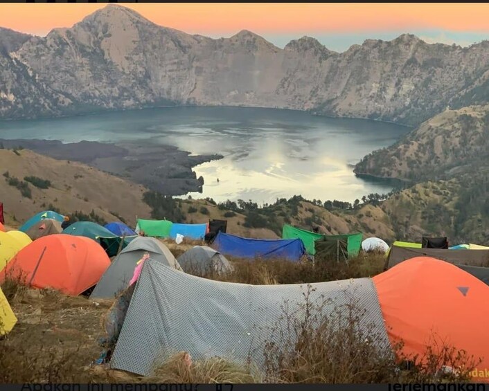 Een bergachtig landschap met een meer en kleurrijke tenten. 2