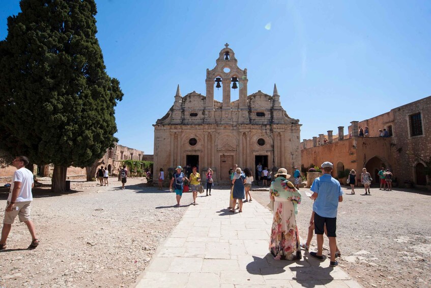 A historic church with a bell tower, surrounded by a plaza with people walking and standing. 2