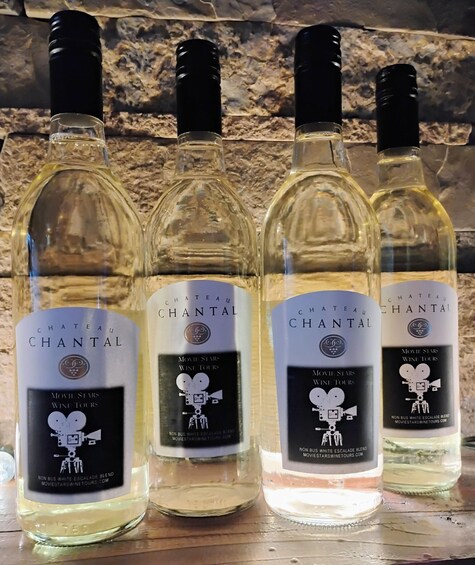 Four bottles of Chateau Chantal wine on a wooden surface with a stone wall in the background. 1