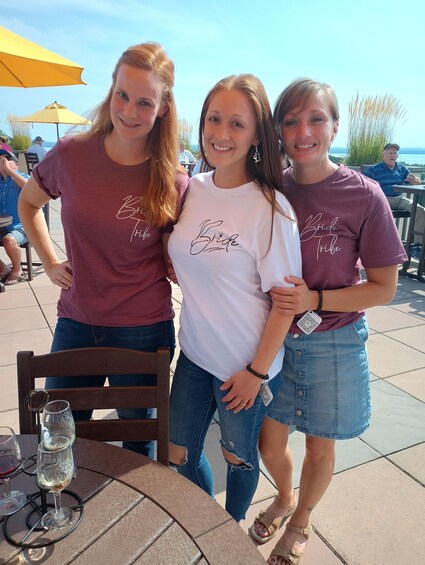 Three people standing at an outdoor table with drinks. 2