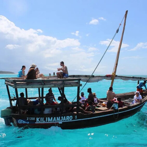 A boat named 'KILIMANJARO' with passengers and a clear blue sea. 1