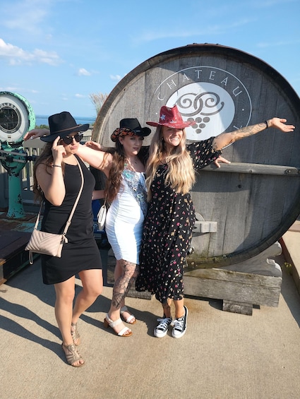 Three people posing in front of a large wooden barrel with the word "CHATEAU" on it. 5