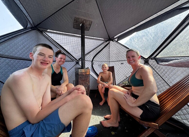 A group of people sitting inside a tent with a chimney. 2