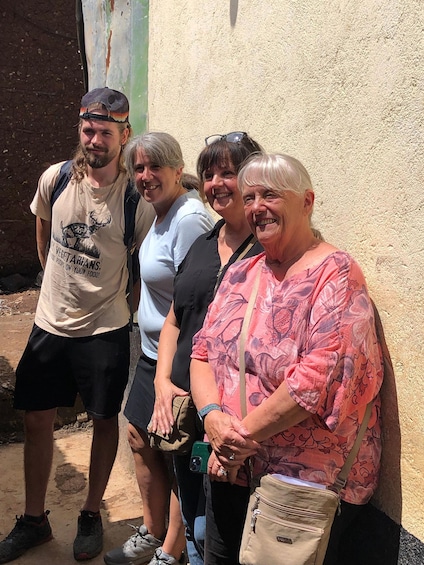 Four people standing outdoors against a wall. 4