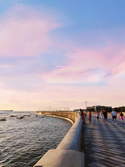 A pier with people walking along it during sunset. 3
