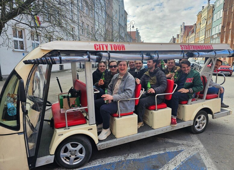 A group of people on a city tour vehicle with 'CITY TOUR' and 'STADTTRUNDFAHRT' written on it. 2