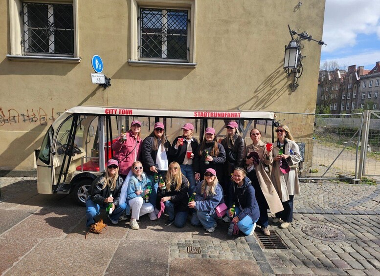 A group of people posing in front of a city tour bus with 'CITY TOUR' and 'STADTTRUNDFAHRT' signage. 5