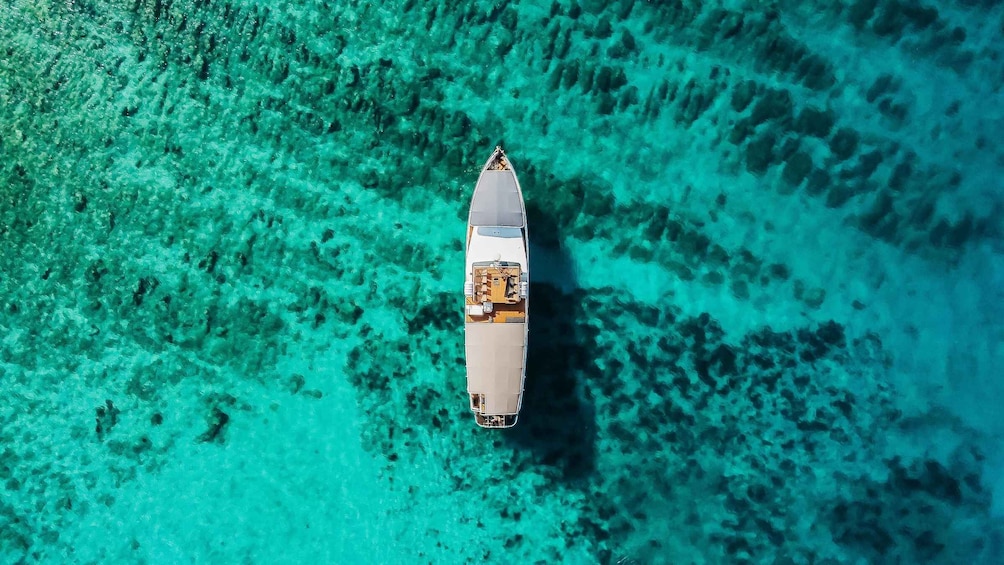 An aerial view of a boat on clear turquoise water. 1
