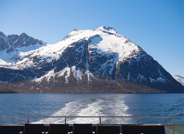 A snow-covered mountain range with a clear blue sky and calm sea. 2