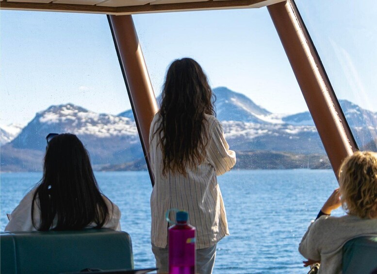 Three people on a boat with a mountainous landscape in the background. 5