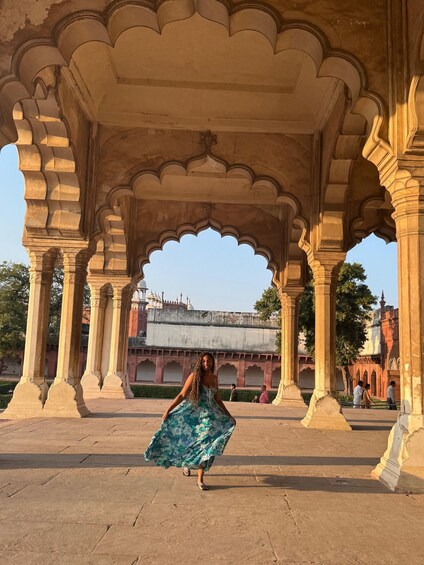 A woman in a blue dress walking through an ornate architectural structure with arches and columns. 5